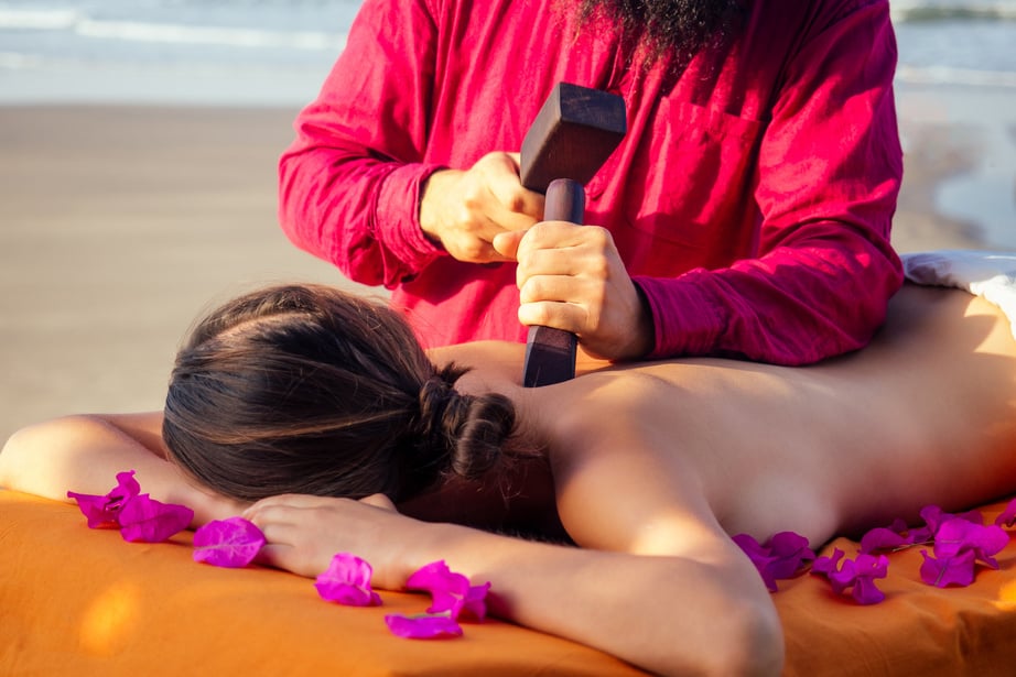 Male Master Makes Thai Massage Tok-Sen Spa  Physiology by the Sea Ocean Beach.Beautiful Woman Having a Relaxing Thai Back Massage with Set for Massage Toksen,Body Care Relaxation Resort